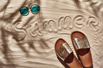 Traveler vacation accessories are laid out on a white beach sand. Flat lay, top view.