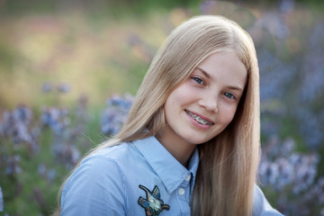 beautiful teen girl with braces on her teeth smiling. portrait of blonde model with long hair in...