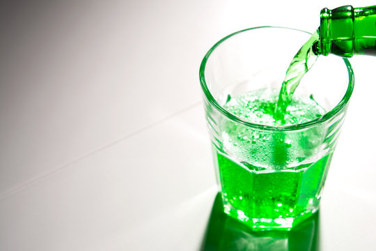 glass with green soda on a white background