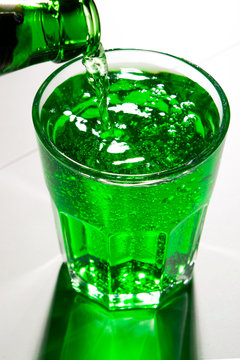 glass with green soda and bottle