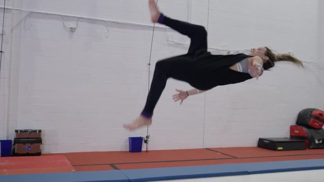 Female athlete doing impressive tumbling on trampolines and gym parcour equipment