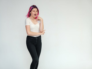 Portrait below the knee of a young beautiful girl teenager in a white T-shirt and black jeans with beautiful purple hair on a white background in the studio. They say, they smile, they show hands