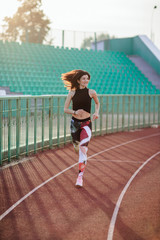Sport. Athletic young brunette woman in pink sneakers, leggings and top run on running track...