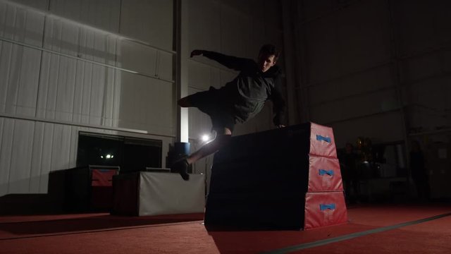 Man training in parcour in the gym with padded equipment and obstacles
