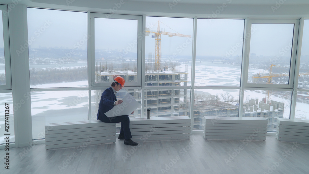 Aufkleber happy building engineer sitting in the modern office looking on the blue print documents with archit