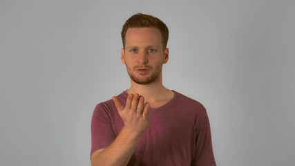 Portrait young caucasian man on grey background. caucasian guy with red hair posing showing hand gesture air kiss. handsome redhead men wearing in casual t-shirt