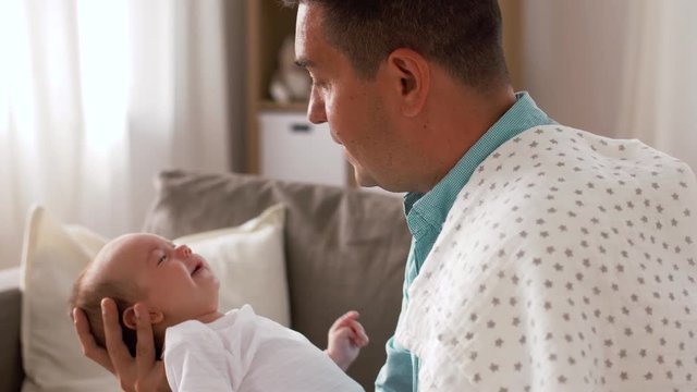 family, parenthood and fatherhood concept - middle aged father comforting crying little baby daughter at home