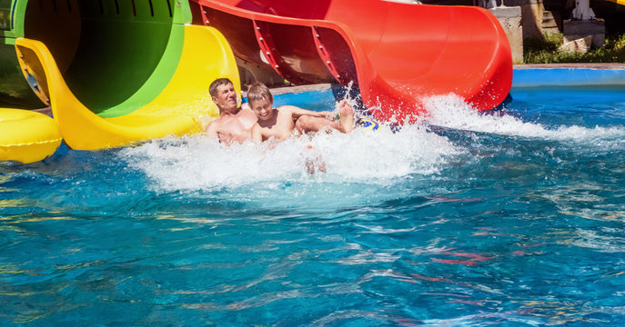 Happy Family Enjoying The Water Park Slide