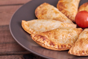 Empanadillas al horno en plato negro con tomate cherry