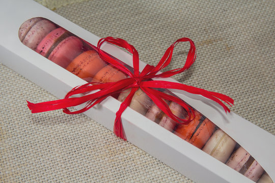 Colorful macaroons in a gift box on the textile background. Gifts and romance