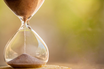 Sand running through the bulbs of an hourglass measuring the passing time in a countdown to a...