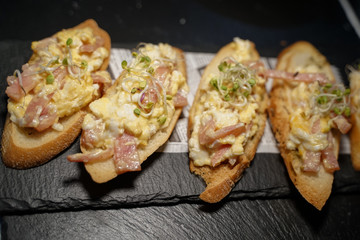 Traditional bruschetta carbonara, cream cheese, eggs and bacon on stone cutting board. Top view - image