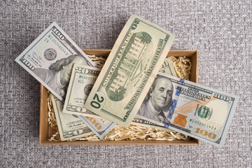 Dollar studio image. Notes in a carton box. Cardboard box with american money. Banknotes in a small...