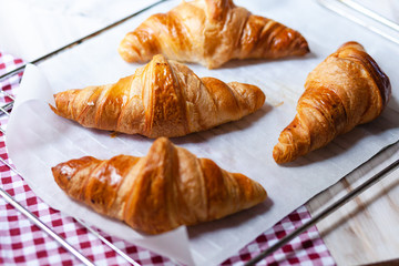 Tray with freshly baked french croissants. Served on a baking paper and red napkin. Perfect breakfast for sunday morning, sweet and delicious homemade pastry