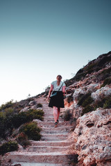 a young girl walking up stone stairs and hiking up the hill in the spanish natural landscape. Mallorca Spain Balearics