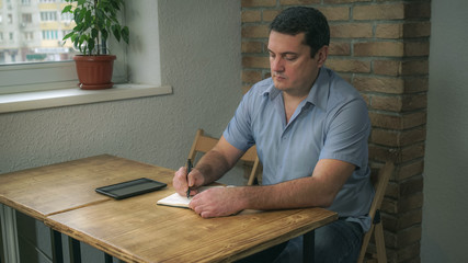 Adult male sitting in a cafe on the table in Kotormo diary he writes, lies next to the plate,...