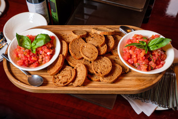 Vegetable tartar on a wooden board with sliced bread on a wooden table