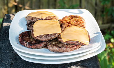 Hamburgers and cheeseburgers patties on a white plate