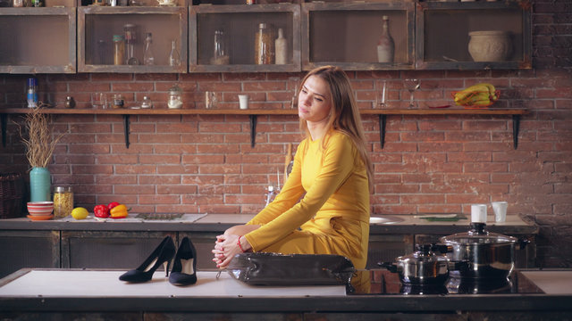 Tired Businesswoman Coming Home After Bad Day. Attractive Lady Sitting On The Chair Put The Shoes On The Table. Exhausted Adult Lady In Kitchen At Home.