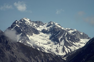 Fototapeta na wymiar Closeup on snowy mountain peak half in sunlight and half in shadow