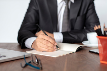 Businessman working on his desk takes notes on his notepad