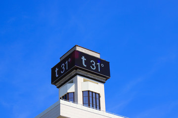 Electronic large thermometer on the building, indicating a high summer air temperature 31 degrees...