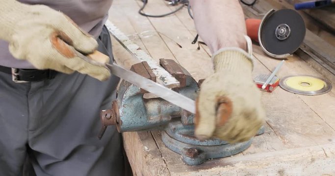 Un homme &eacute;bavure une pi&egrave;ce de m&eacute;tal avec une lime 