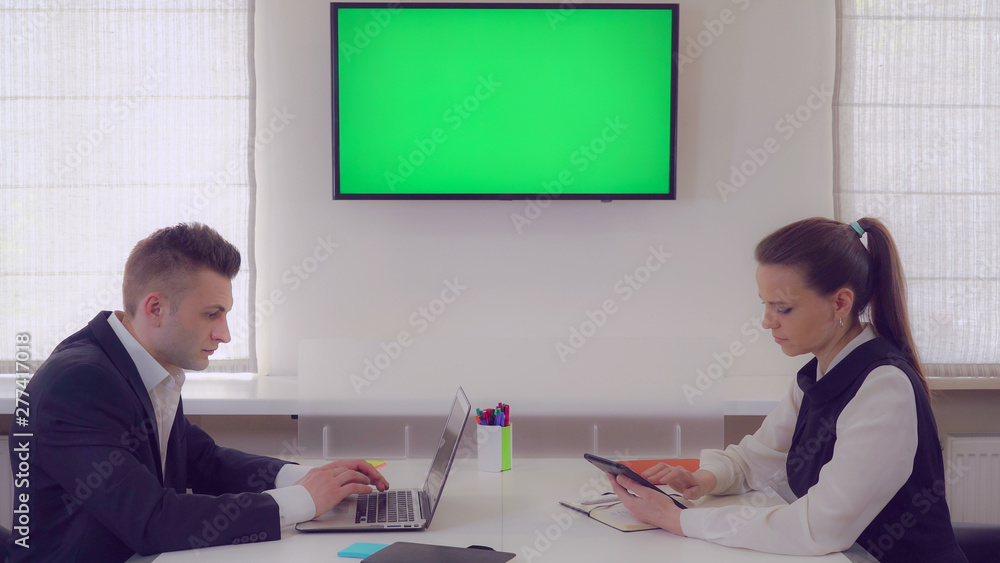 Poster managers focused at work finalizing presentation. co workers sitting in boardroom using laptop. two 
