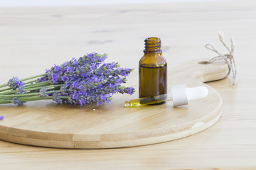 Essential lavender oil in the bottle with dropper on wooden desk. Horizontal close-up.
