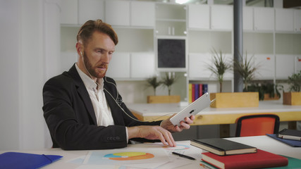 Businessman looks at charts and talking to a tablet. Video UHD