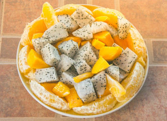 Fresh exotic tropical fruit salad with dragonfruit, mango and orange on plate