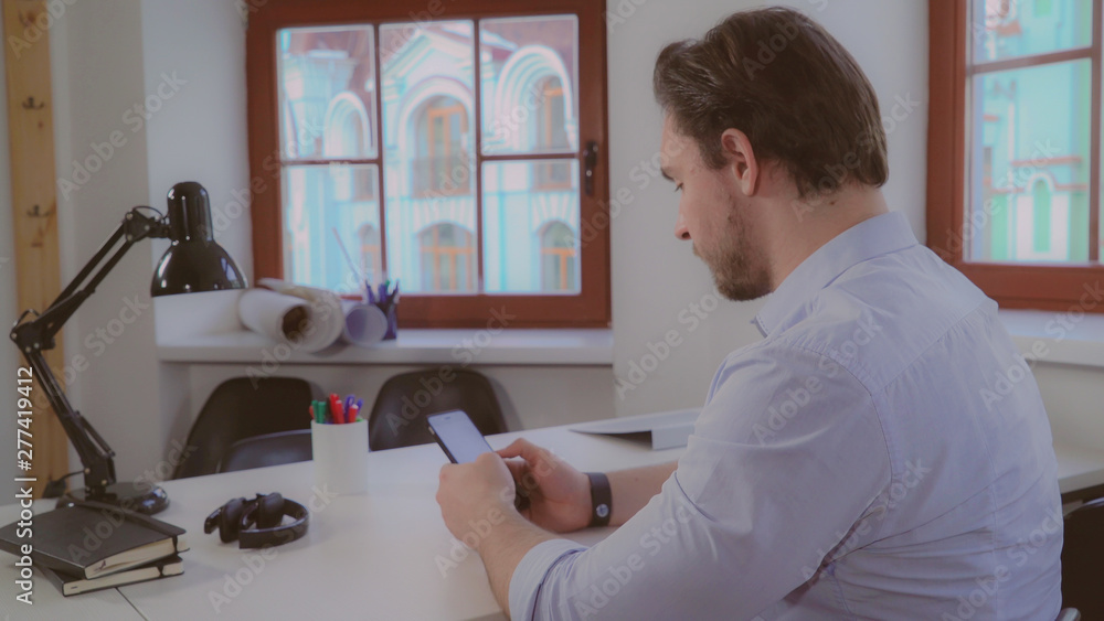 Poster designer or architect working in the office. man wearing in casual clothes sitting at the desk near 