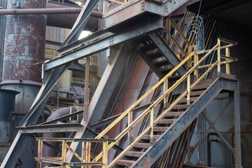 Complex industrial site with stairs and pipes,heavily textured paint and rust patinas, horizontal aspect
