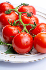 Bunch of fresh ripe red tomatoes with leaves on board and  white background