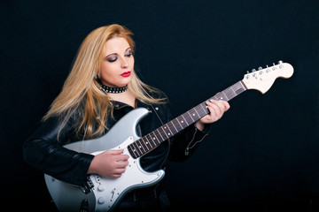 Fototapeta na wymiar Beautiful blonde girl in rock style on a black background.