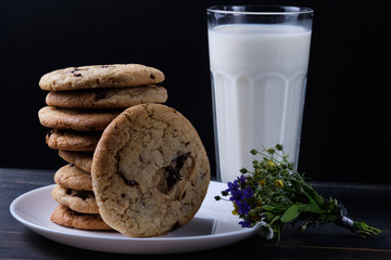 American chocolate chip cookies. Cookies, a glass of milk , flowers and a linen towel. Rustic still life.