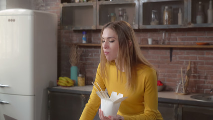 Woman eating chinese food to go. Lady enjoy dish at home use laptop. Adult businesswoman eats and working at the same time.