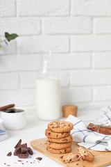 Morning breakfast with hot ground coffee with cinnamon, sweet pastry with chocolate, a bottle of fresh milk on a white brick wall background with space for text