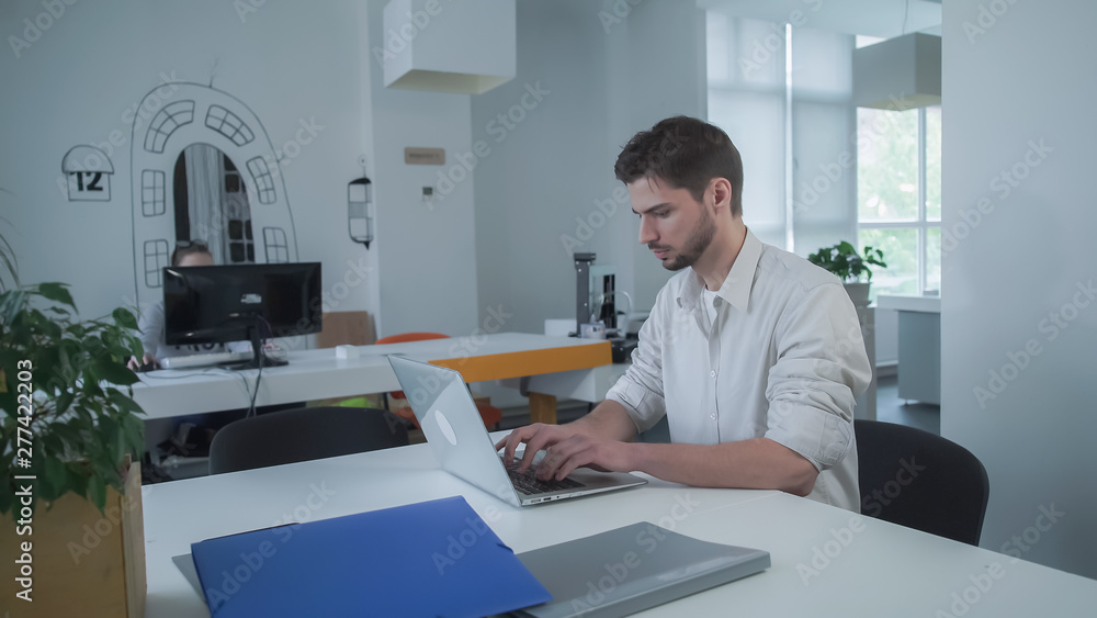 Poster worker using computer. businessman typing on laptop. young mixed race employee concentrated at the w