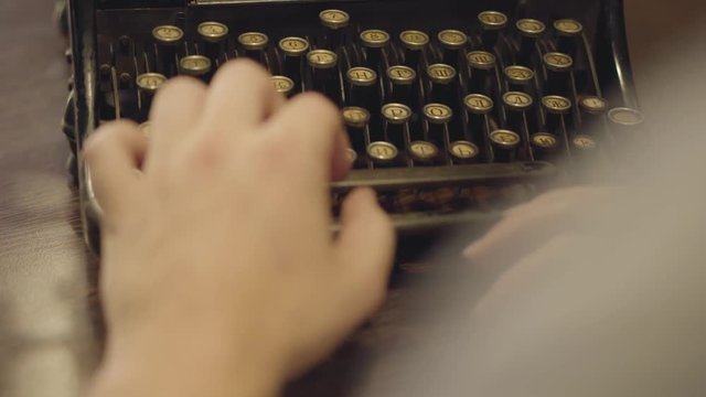 Female hands slowly typing on the old typewriter with russian letters close-up. Shooting behind the back. Work with rare things.