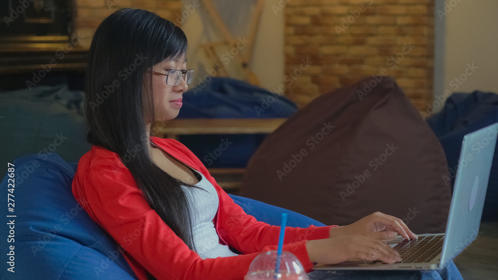 Aufkleber young asian woman sitting in the cafe using laptop. beautiful girl typing on computer chatting in so