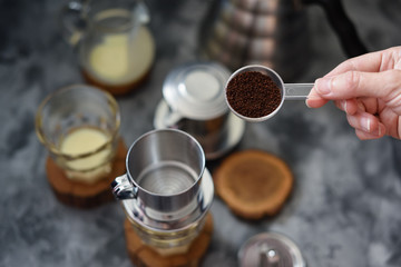 Making pour over Vietnamese milk coffee. Woman hand pouring coffee into phin on dark background