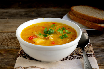 Vegetarian soup with vegetables and pasta on a wooden table.
