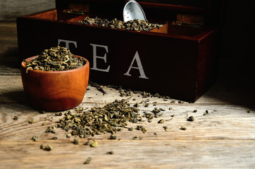 A collection of varieties of tea in a special tea box, a special ceramic spoon and wooden utensils.