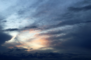 Sunset on colorful sky, sun shining through the dark clouds. Picturesque landscape for background
