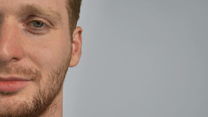 close up face young caucasian man with beard, looking at the camera with smile. Male with blue eyes and bristle