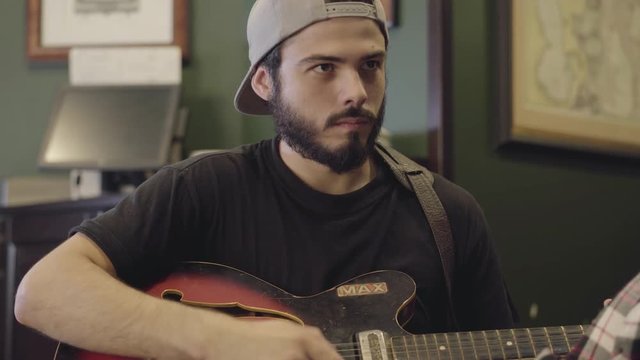 Skill young bearded man playing guitar in the bar. Leisure at the beer pub.