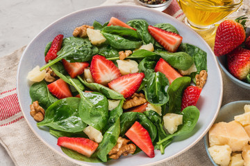 summer strawberry salad with spinach leaves, parmesan cheese, olive oil and walnuts. healthy keto diet food