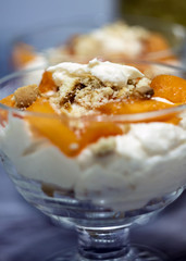 Glass filled with cream and parts of fruit and biscuits