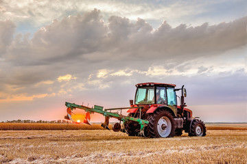 A tractor with a plow. Plowing the field after harvest .